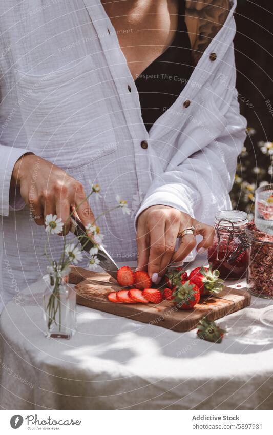 Erdbeeren für ein Sommerfrühstück im Freien vorbereiten Frau Frühstück Gesundheit Schneiden hölzern Holzplatte natürlich Licht Blume unkenntlich anonym