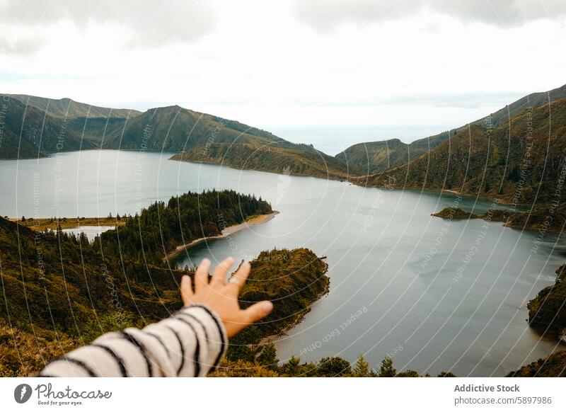 Die Hand zeigt auf eine malerische Aussicht auf die Lagoa do Fogo, Sao Miguel, Azoren. São Miguel Landschaft Aussichtspunkt Wasser See Hügel Wolken Himmel Natur