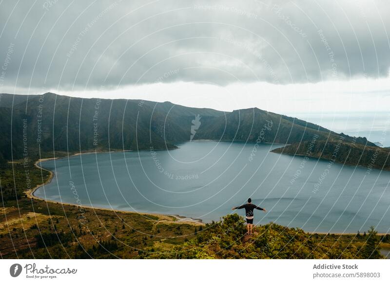 Mann genießt den Panoramablick auf einen See in Sao Miguel, Azoren. São Miguel Berge panoramisch Ansicht Einsamkeit Natur üppig (Wuchs) Bergkuppe Gelassenheit