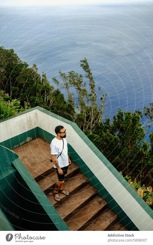 Mann auf einer Treppe mit Blick auf den Ozean von Sao Miguel. Treppenhaus Meer São Miguel Azoren Ansicht üppig (Wuchs) Laubwerk Landschaft MEER reisen Natur