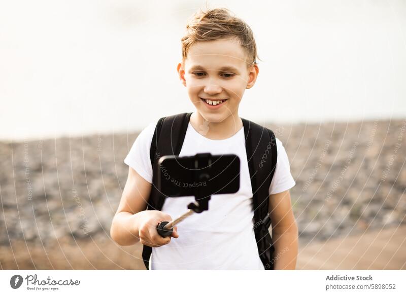 Teenager, der im Park einen Vlog mit seinem Smartphone aufnimmt Junge Selfie im Freien vlog Handy Aufnahme Video Technik & Technologie Apparatur Gerät Lächeln