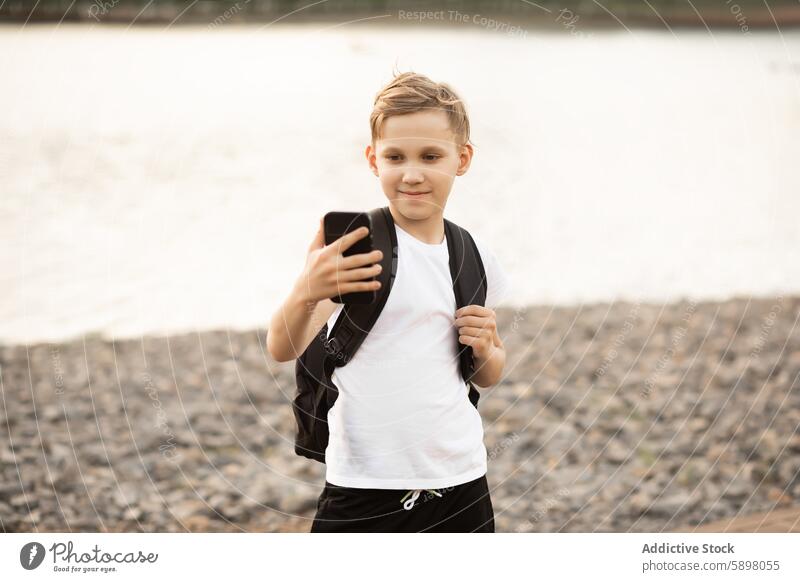 Jugendlicher nimmt Selfie im Park in der Nähe eines Sees mit Smartphone Teenager Junge Handy im Freien Blogger Reisender Video vlog Gerät Apparatur Teich