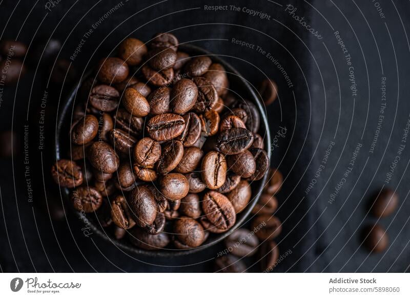 Luftaufnahme von frischen ganzen Kaffeebohnen in einer dunklen Schale Schalen & Schüsseln Textur dunkel braun glänzend aromatisch Koffein Braten dunkle Röstung