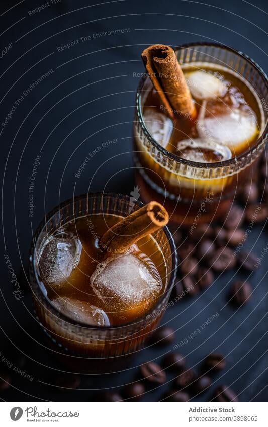 Nahaufnahme eines kalten Kaffeegetränks, garniert mit Zimt trinken Glas Eis Würfel Bohne gekühlt Getränk dunkel Oberfläche Hintergrund Garnierung Aroma