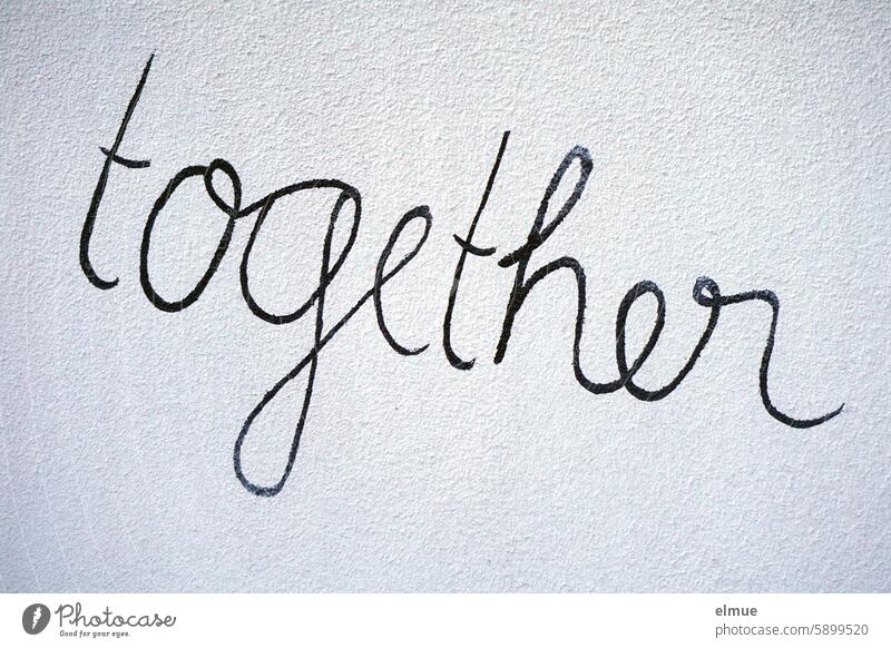 together steht in schwarzer Schreibschrift an einer grauen Wand zusammen gemeinsam miteinander gleichzeitig beisammen englisch Schriftzug Blog Mitteilung