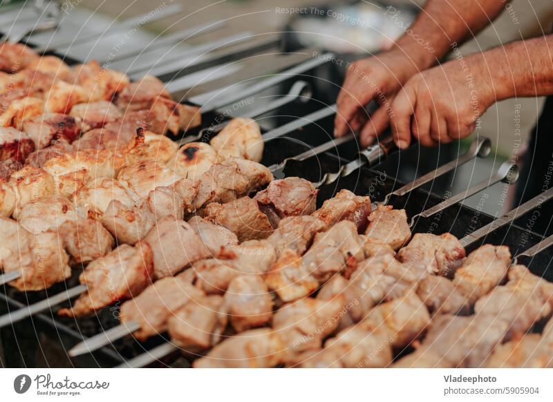 Braten Schaschlik am Spieß im Kohlenbecken. Frisches rotes Fleisch für den Grill auf dem Feuer im Freien Lebensmittel Barbecue Kebab Essen zubereiten Picknick