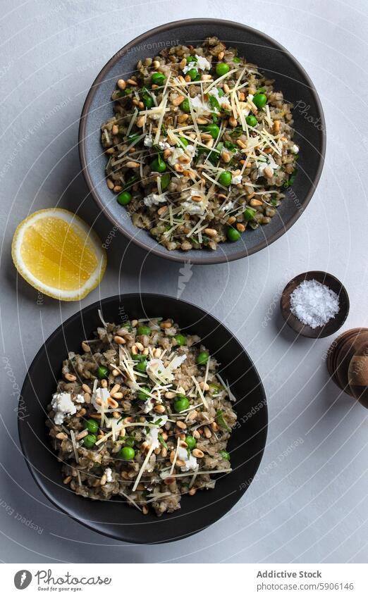 Gerstenrisotto mit Erbsen und gehobeltem Käse Overhead Shot Risotto Raspelkäse Zitrone Salz Schalen & Schüsseln Lebensmittel Garnierung Ansicht von oben