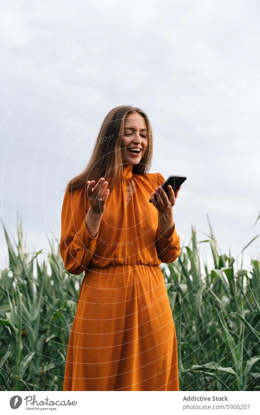 Brünette Frau benutzt Smartphone in einem Maisfeld brünett Kornfeld orangefarbenes Kleid Glück im Freien lässig Feld Freude Engagement Handy Mitteilung