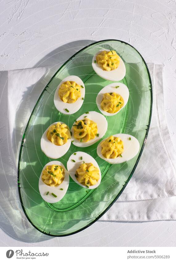 Leckere deviled eggs auf einer grünen Glasplatte, Ansicht von oben Ei Platte Draufsicht Sonnenlicht Schatten weiß Hintergrund Schnittlauch Garnierung cremig