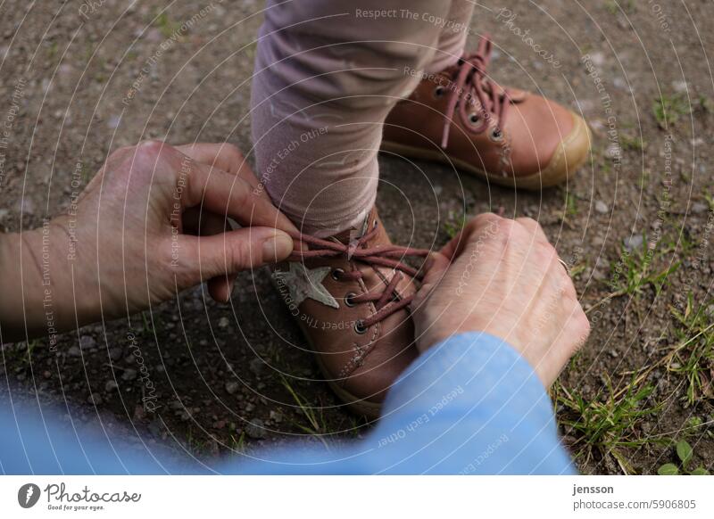 Nahaufnahme von Händen, die kleine Kinderschuhe zubinden Hand Schuhe Schuhe zubinden Schnürsenkel Nahaufnahme bei natürlichen Beleuchtungsverhältnissen