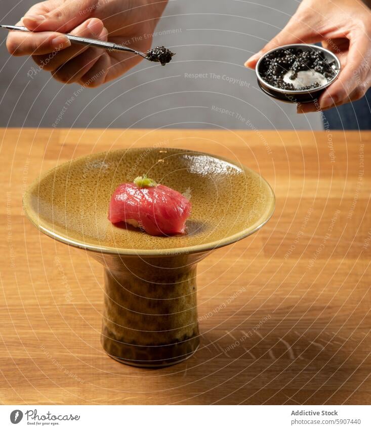 Der letzte Schliff für Sushi mit Kaviar Garnierung Hand Keramik Teller Textur Nahaufnahme Meeresfrüchte Küche Japanisch Delikatesse Vorbereitung