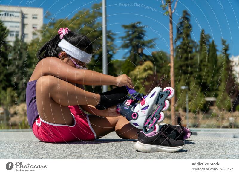 Junges Mädchen auf Rollschuhen in einem sonnigen Park Rollerblade Baum Straßenbelag Konzentration Gurt Schlittschuh Spaß Tag Schlittschuhlaufen farbenfroh