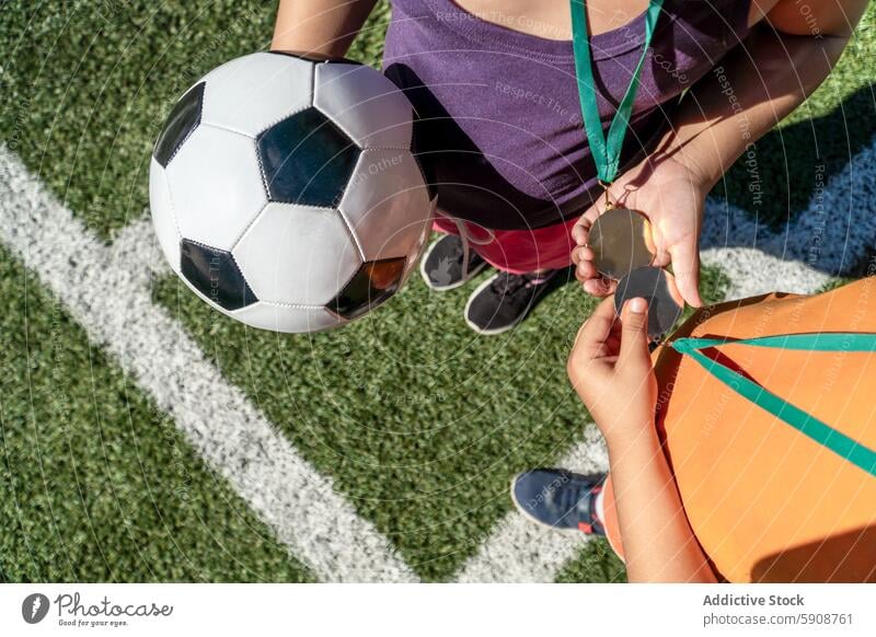 Kinder tauschen Medaillen aus und halten einen Fußball auf dem Spielfeld Sport Team Teamwork Sportlichkeit Feld Wechseln Overhead Ansicht spielen Konkurrenz