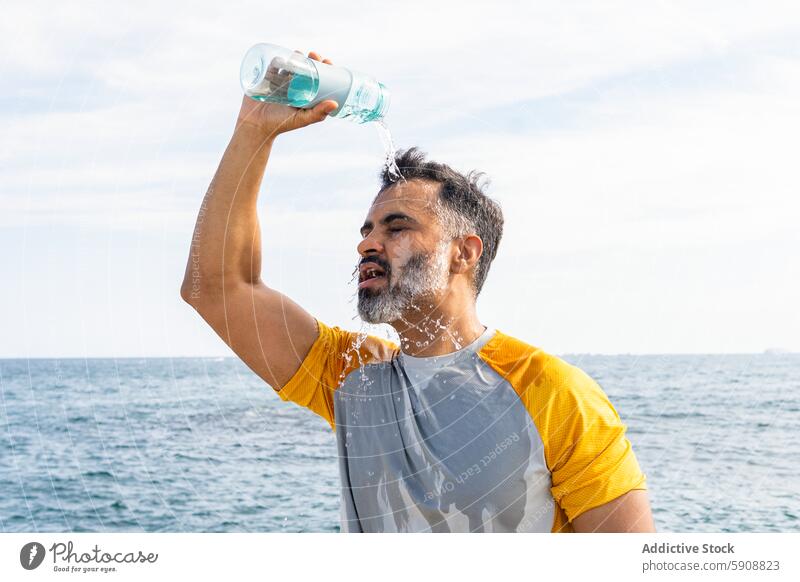 Indischer Mann, der sich an einem Sommertag am Meer mit Wasser abkühlt Inder MEER Erfrischung Abkühlung sonnig Tag im Freien Hydratation Gesundheit Freizeit