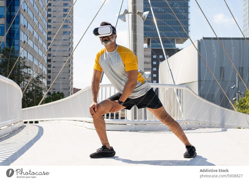 Indischer Mann mit VR-Headset beim Sport in einer städtischen Umgebung Inder Virtuelle Realität vr-kopfhörer trainiert. urban Großstadt Wolkenkratzer Brücke