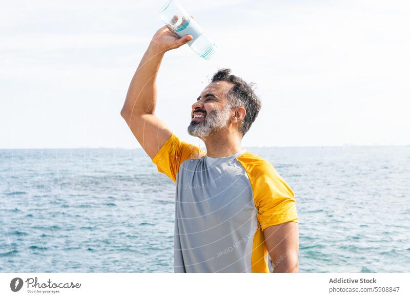 Indischer Mann, der sich an einem Sommertag am Meer mit Wasser abkühlt Inder MEER Erfrischung Abkühlung sonnig Tag im Freien Hydratation Gesundheit Freizeit