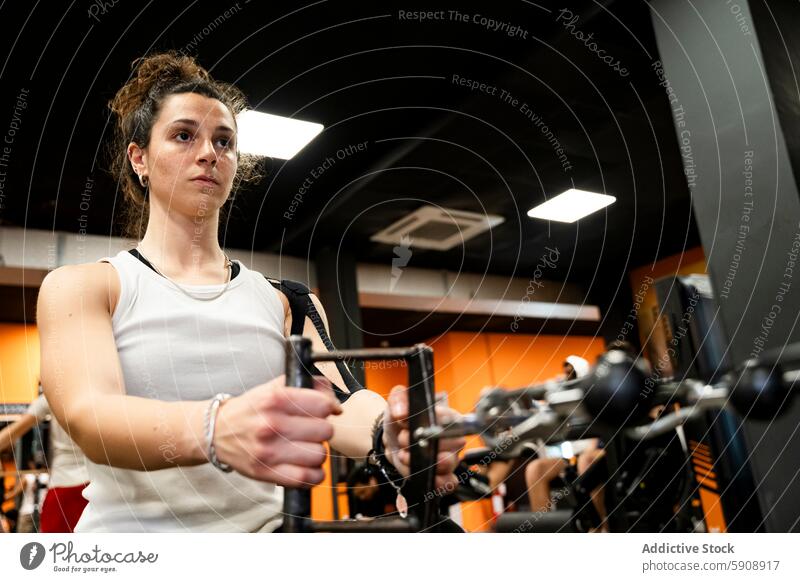 Junge Frau konzentriert sich auf Kraftdreikampf im gut ausgestatteten Fitnessstudio Training Gewichte Tatkraft modern Gerät schwer Sitzung Übung Muskel Stärke