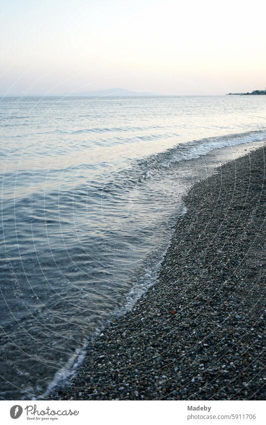 Blick vom Strand in Altinoluk im romantischen Licht der untergehenden Sonne auf den Golf von Edremit am Ägäischen Meer in der Provinz Balikesir in der Türkei