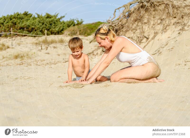 Mutter und kleiner Sohn genießen die gemeinsame Zeit an einem Sandstrand Strand spielen Familie Kind Frau Sommer Urlaub Feiertag Italien Düne Vegetation sonnig