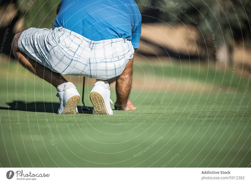 Rückenansicht eines nicht erkennbaren männlichen Golfspielers auf dem Grün Golfer Sport Rückansicht unkenntlich anonym gesichtslos hockend Putten Kurs grün