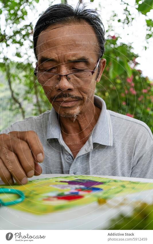 Älterer vietnamesischer Mann näht einen bunten Stoff Vietnamesen älter Nähen Handwerkskunst Gewebe farbenfroh im Freien traditionell Handnähen Fokus männlich