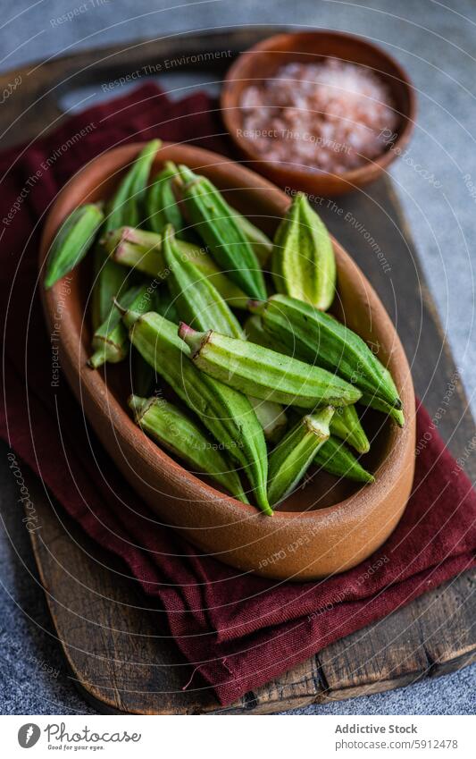 Rohe Bamia-Schoten in einer rustikalen Schale, bereit für die mediterrane Küche okra bamia roh Gemüse Schalen & Schüsseln hölzern Pinksalz Himalaja-Salz frisch