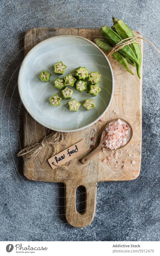 In Scheiben geschnittene Bamia auf Holzbrett mit Rohkostanhänger und Gewürzen bamia okra roh aufgeschnitten Gemüse rustikal mediterran Küche Lebensmittel Dill