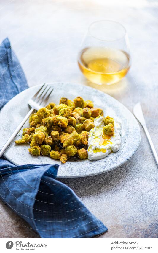 Gebratene Bamia mit Sauerrahmsauce, Dill und Knoblauch auf einem Teller bamia gebraten Saucen mediterran Lebensmittel Speise Wein Glas Weißwein Küche Gemüse