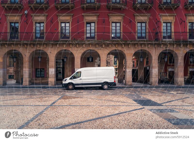 Auf einem historischen Platz in Gijon, Spanien, geparkter Lieferwagen gijon weißer Lieferwagen Plaza gepflastert rotes Gebäude Bögen Fahrzeug Architektur