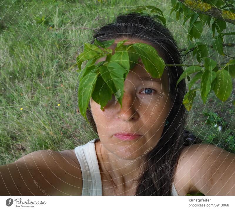 Blatt-Piratin: nach oben blickende Frau mit natur-grüner Augenklappe. Grün baum natürliche Schönheit natürliche Umgebung Natur schlicht leben Kraft Energie