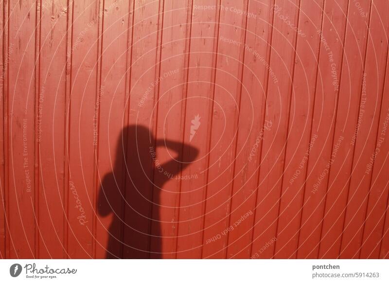 blick voraus. schatten eines kindes auf roter bretterwand sonne bewegung ausblick zukunft arm körper Außenaufnahme Farbfoto Schönes Wetter