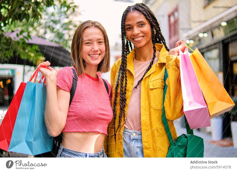 Zwei glückliche Frauen beim gemeinsamen Einkaufen in der Stadt Tasche Großstadt urban Freund Lächeln Glück Freude farbenfroh Einzelhandel Verbraucher Sale Kauf