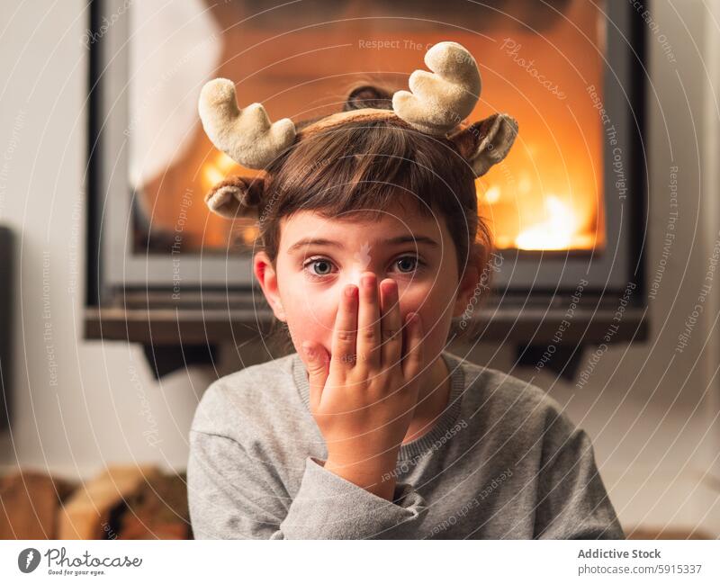 Kleines Mädchen mit Rentiergeweih bei der Weihnachtsfeier Kind Weihnachten Feier Hirschgeweih Überraschung Feuerstelle gemütlich festlich heimwärts Freude jung