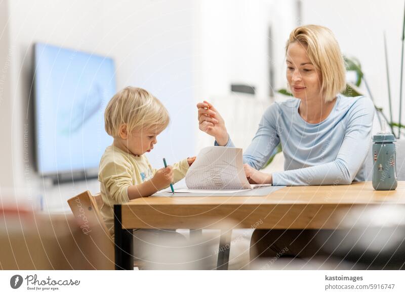 Caring junge kaukasische Mutter und kleinen Sohn Zeichnung Malerei in Notebook zu Hause zusammen. Liebevolle Mutter oder Kindermädchen mit Spaß am Lernen und Spielen mit ihrem kleinen 1,5 Jahre alten Säugling Baby Junge Kind.