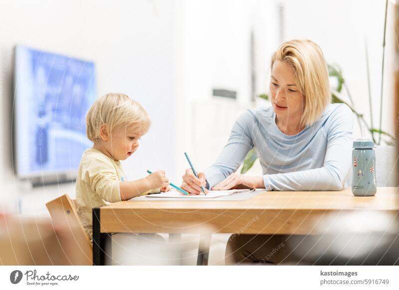 Caring junge kaukasische Mutter und kleinen Sohn Zeichnung Malerei in Notebook zu Hause zusammen. Liebevolle Mutter oder Kindermädchen mit Spaß am Lernen und Spielen mit ihrem kleinen 1,5 Jahre alten Säugling Baby Junge Kind.