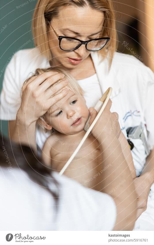 Kleinkind, das von einem Kardiologen im Rahmen der regelmäßigen ärztlichen Untersuchung beim Kinderarzt mit einer Ultraschalluntersuchung auf Herzgeräusche untersucht wird.