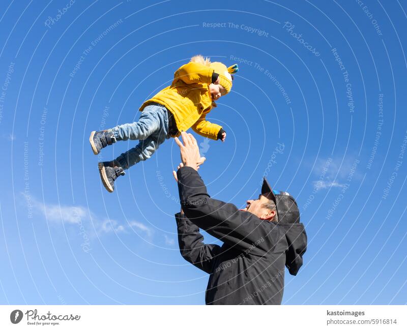 Mehr, mehr,...Papa, das macht Spaß. Glücklicher junger Vater wirft sein süßes kleines Baby in die Luft. Vatertag, Vater und sein Sohn Baby Junge spielen und umarmen im Freien in der Natur im Herbst.