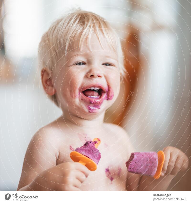 Glücklich liebenswert Säugling Baby Junge Kind lächelnd beim Essen zwei gefrorene Früchte Eis am Stiel in simmer. Stieleis Speiseeis Sahne Lebensmittel Sommer