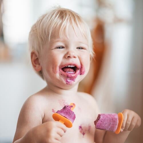 Glücklich liebenswert Säugling Baby Junge Kind lächelnd beim Essen zwei gefrorene Früchte Eis am Stiel in simmer. Stieleis Speiseeis Sahne Lebensmittel Sommer