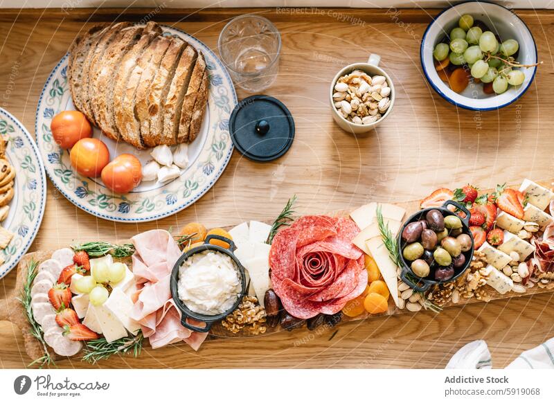 Draufsicht auf ein Gourmet-Charcuterie-Brett mit verschiedenen Leckereien Käse geräuchertes Fleisch Frucht Brot Nut Tisch Feinschmecker Kunstgewerbler Reichtum