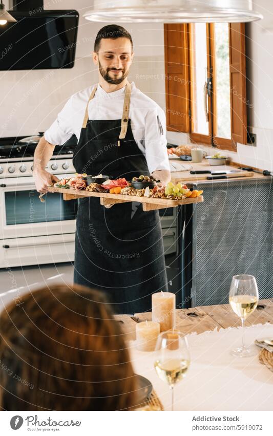 Privatkoch serviert Freunden in der Küche ein Gourmet-Menü Küchenchef speisend unkenntlich anonym Feinschmecker Charcuterie Mahlzeit Platte Holzplatte Käse