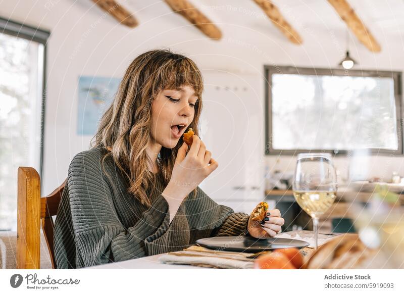 Frau genießt eine Krokette in einer stilvollen Inneneinrichtung speisend heimwärts Lifestyle Genuss Mahlzeit im Innenbereich modern gemütlich Tisch Lebensmittel