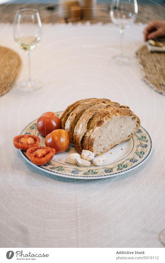 Elegantes Essgeschirr mit frisch geschnittenem Brot und Tomaten Tisch speisend aufgeschnitten Knoblauch Weinglas Teller dekorativ Mahlzeit anspruchsvoll reif