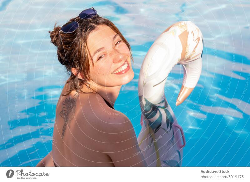 Junge Frau lächelnd in einem Pool mit aufblasbaren Lächeln sonnig Schwimmer Freude Fröhlichkeit Sommer Wasser Freizeit Spaß Erholung Tattoo schwimmen im Freien