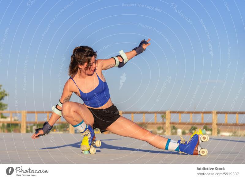 Junge Frau, die im Freien fortgeschrittene Rollschuh-Tricks vorführt Rollerskate Athletik Fähigkeit jung energetisch Sport Schlittschuhlaufen Klarer Himmel