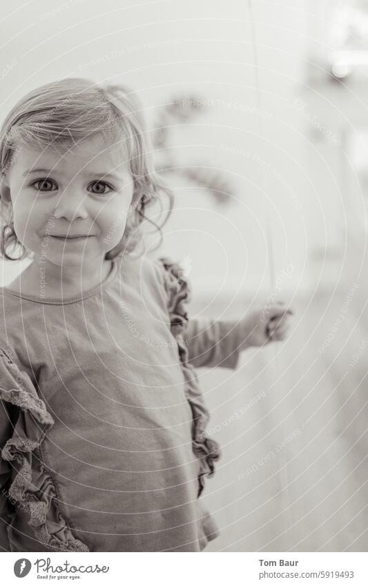 kleines Mädchen lächelt in die Kamera Mädchenportrait Schwarzweißfoto lockiges haar Blick in die Kamera Lächeln lächelnd Lächelndes Gesicht große Augen Freude