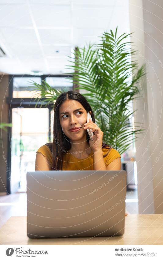 Beschäftigte Frau, die mit ihrem Smartphone spricht und einen Laptop benutzt benutzend abgelegen Tippen Telefonanruf Arbeit zuschauen Projekt freiberuflich