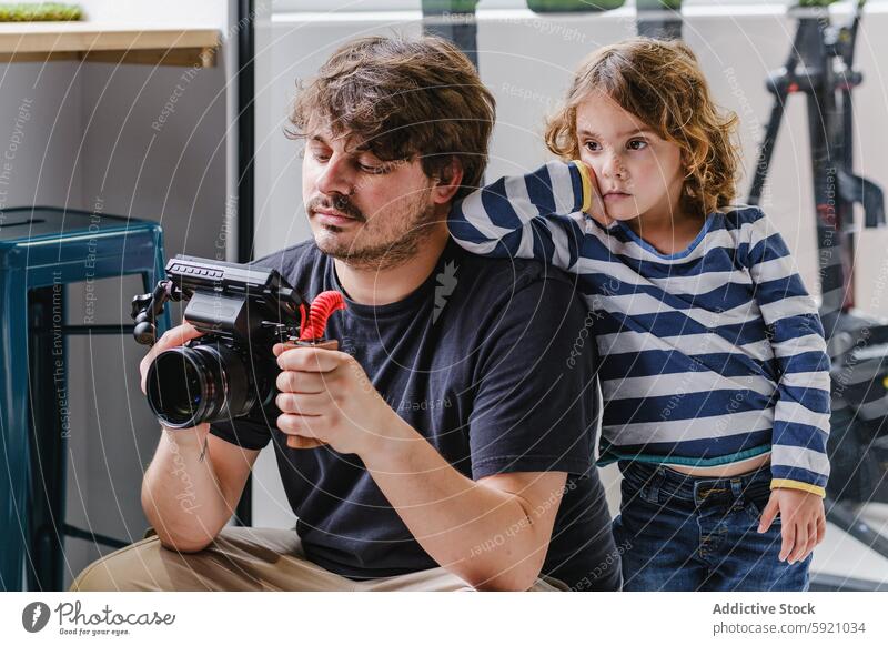 Junger Filmemacher mit einem Kinderassistenten bei der Kontrolle der Ausrüstung Fotokamera Assistent Neugier Atelier Video Gerät überblicken Filmmaterial