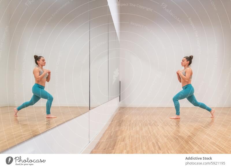 Frau übt Anjaneyasana Yoga-Pose mit Reflexion anjaneyasana üben Spiegel Reflexion & Spiegelung Atelier minimalistisch Gesundheit Wohlgefühl Fitness Übung