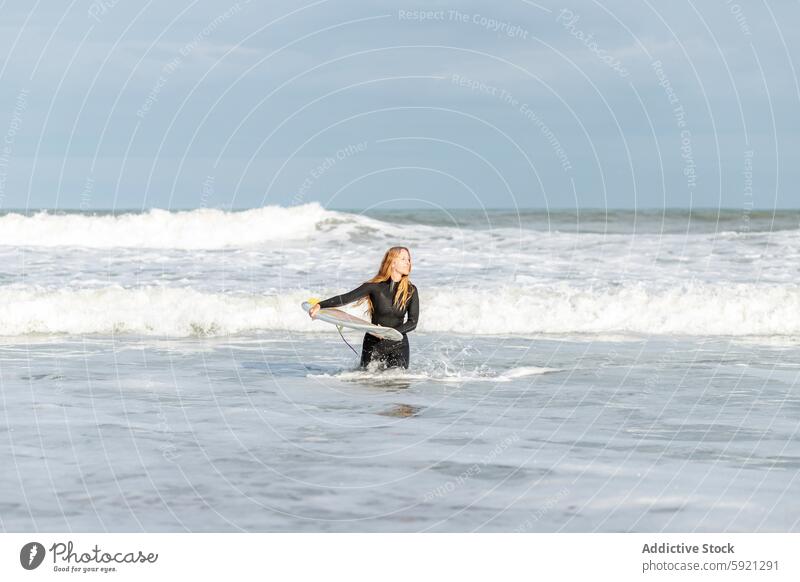 Frau mit Surfbrett im Meer in die Kamera schauen Hobby Aktivität Zeitvertreib Sport MEER Wasser Ufer Strand Gezeiten winken Hafengebiet Seeküste Natur Gerät